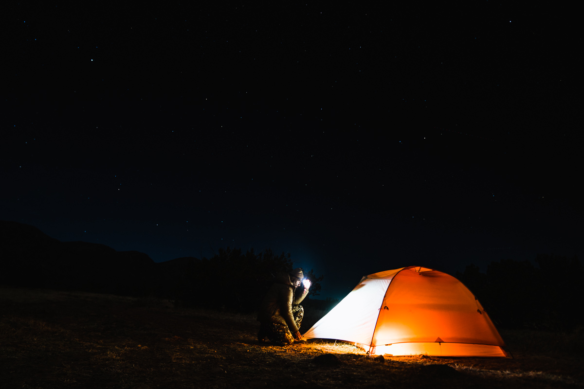 Josh Kirchner at the base of his backcountry shelter at night